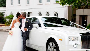 Couple kissing in front of wedding limo